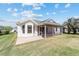 Exterior rear view of home featuring an enclosed porch and lush landscaping at 1854 Oxford Lane, The Villages, FL 32162