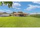 Expansive backyard featuring a well-manicured lawn and partial view of the light-colored home with screened in lanai at 22 Banyan Dr, Ocala, FL 34472