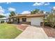 View of home with attached garage, green lawn, and colorful garden bed at 22 Banyan Dr, Ocala, FL 34472