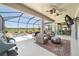This screened-in patio features seating, ceiling fans, a TV, and golf course views near the water feature at 6865 Sw 97Th Terrace Rd, Ocala, FL 34481