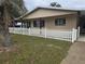 Home exterior showing well-maintained lawn and charming white picket fence near trees at 10040 Sw 98Th Ave, Ocala, FL 34481