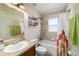 Bright bathroom features a shower-tub combo, granite vanity, and decorative shelving for storage at 10400 Sw 50Th Ct, Ocala, FL 34476