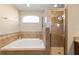 Large soaking tub and separate glass shower, tiled in earth tones, with a large window at 10400 Sw 50Th Ct, Ocala, FL 34476
