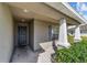 Covered front porch with a gray front door, and landscaped entryway at 10400 Sw 50Th Ct, Ocala, FL 34476