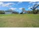 Expansive backyard with lush green grass, house with screened-in patio, and separate wooden pavilion structure at 11707 Se 101St Court Rd, Belleview, FL 34420