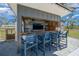 Outdoor bar with three blue stools, tv and a dark countertop at 11707 Se 101St Court Rd, Belleview, FL 34420