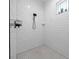 Clean white tile shower with a black shower head fixture and black tiled floor at 11707 Se 101St Court Rd, Belleview, FL 34420