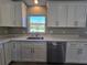 Well-lit kitchen showcasing white cabinets, stainless steel dishwasher, and a sink with a window view at 15 Locust Trak, Ocala, FL 34472