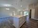 Open-concept living space with kitchen island, modern lighting, and durable gray flooring at 15 Locust Trak, Ocala, FL 34472
