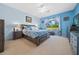 Light blue main bedroom with patterned bedding, dark furniture and a large window overlooking the yard at 15092 Sw 14Th Avenue Rd, Ocala, FL 34473