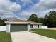 Charming single-story home with a two-car garage, green lawn, and a combination of trees and cloudy blue sky at 2722 Sw 151St Ave, Ocala, FL 34481