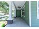 Inviting front porch with stone pillars, ceiling fan, and green siding at 2735 Se 19Th Ct, Ocala, FL 34471