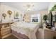 Cozy bedroom with floral bedding, side tables, and a bright window with sheer curtains at 3407 Melbourne Ln, The Villages, FL 32163