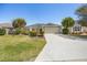Well-maintained home featuring a manicured lawn, mature trees, and a spacious driveway at 3407 Melbourne Ln, The Villages, FL 32163