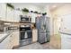 Well-equipped kitchen featuring stainless steel appliances, white cabinetry, and tiled floors at 3407 Melbourne Ln, The Villages, FL 32163