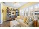 Bright living room featuring shuttered windows, a sofa with an ottoman, and built-in shelves at 3407 Melbourne Ln, The Villages, FL 32163