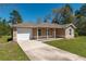 Inviting home with an attached garage and covered porch, complemented by a green lawn and clear blue skies at 4421 Sw 139 Pl, Ocala, FL 34473