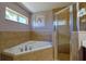 Bathroom featuring a soaking tub with tile surround, glass shower, and window at 5037 Sw 109Th Loop, Ocala, FL 34476