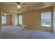Large main bedroom with carpet, a ceiling fan, a tray ceiling, and views of the outdoors at 5037 Sw 109Th Loop, Ocala, FL 34476
