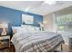 Inviting bedroom featuring a queen-size bed, wood floors, a blue accent wall, and bright natural light at 5150 Se 47Th Court Rd, Ocala, FL 34480