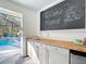 Pool house includes sink, counter and chalkboard welcome message that overlooks screened-in pool at 5150 Se 47Th Court Rd, Ocala, FL 34480