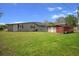 Backyard features green grass, a storage shed, and ample space for various outdoor activities at 5615 Se 113Th Pl, Belleview, FL 34420
