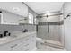Modern bathroom with a double sink vanity, a sliding glass door shower, and stylish gray and white tile at 5615 Se 113Th Pl, Belleview, FL 34420