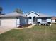 Single-story home with a light blue exterior, grey roof, landscaping, and an attached two-car garage at 7407 Sw 112Th Pl, Ocala, FL 34476