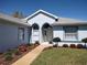 Close up of light blue single story home with arched window above white front door and manicured landscaping at 7407 Sw 112Th Pl, Ocala, FL 34476