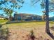 Backyard view featuring a screened-in patio with a stone retaining wall and lush green lawn at 7527 Sw 97Th Terrace Rd, Ocala, FL 34481