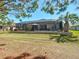 Backyard view featuring a screened-in patio with a stone retaining wall, a lush green lawn and palm trees at 7527 Sw 97Th Terrace Rd, Ocala, FL 34481
