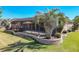 Wide backyard view showing lush green lawn, stone retaining wall and mature palm, with screened patio at 7527 Sw 97Th Terrace Rd, Ocala, FL 34481