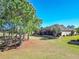 Wide backyard view showing lush green lawn, stone retaining wall, mature palms and screened patio at 7527 Sw 97Th Terrace Rd, Ocala, FL 34481