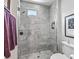 Shower with glass door, showerhead, small window, and gray tile at 8033 Nw 28Th St, Ocala, FL 34482