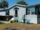 Quaint single-story home features light blue siding, black shutters and colorful landscaping at 8106 County Road 109, Lady Lake, FL 32159