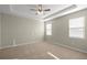 Primary bedroom featuring tray ceiling, ceiling fan and two windows at 8899 Sw 50Th Ave, Ocala, FL 34476