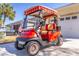 Close up of a red and tan golf cart parked in front of a house with a visible American flag at 9458 Sw 93Rd Loop, Ocala, FL 34481
