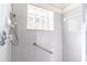 Clean shower stall featuring gray tile, a glass block window, and accessibility features for safety at 9458 Sw 93Rd Loop, Ocala, FL 34481