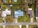 Aerial view of a home with a large yard, screened in patio, mature trees, and a blue metal roof at 12453 Se 61St Ct, Belleview, FL 34420