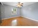 Empty bedroom with light grey walls, wood floors, a window, and a ceiling fan at 12453 Se 61St Ct, Belleview, FL 34420