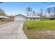 Exterior view of a one-story home with a large driveway, garage, and well-maintained lawn at 12453 Se 61St Ct, Belleview, FL 34420