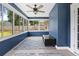 Bright sunroom features large windows, ceiling fan, textured blue walls, and tile flooring at 12453 Se 61St Ct, Belleview, FL 34420