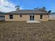 Back exterior view of tan one-story home with sliding glass doors and a small patio at 13 Locust Trak, Ocala, FL 34472