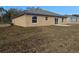 Back exterior view of tan one-story home with sliding glass doors and a small patio at 13 Locust Trak, Ocala, FL 34472
