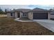 Tan, one-story home with a dark garage door and walkway leading to the front door at 13 Locust Trak, Ocala, FL 34472