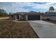 Tan, one-story home with a dark garage door and a long driveway at 13 Locust Trak, Ocala, FL 34472