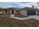 Tan, one-story home with a dark garage door and walkway leading to the front door at 13 Locust Trak, Ocala, FL 34472