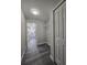 Hallway with gray wood-look floors leads to a kitchen with white cabinets and a laundry room with shelving at 13 Locust Trak, Ocala, FL 34472