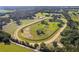 Overhead view of the horse racetrack surrounded by verdant fields and mature trees at 13800 Ne Jacksonville Road, Citra, FL 32113