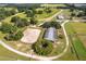 Horse property featuring a large barn and a training arena, with green fields and wooded areas surrounding the property at 13800 Ne Jacksonville Road, Citra, FL 32113